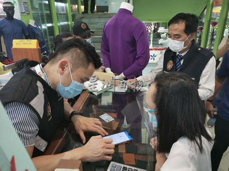 民都鲁卫生局局长钟贤亮协助超市职员注册MySejahtera软件。
