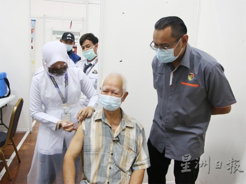来自冷宜新村的赖先生进行注射疫苗，获得莫哈末法扎（右）为他打气。