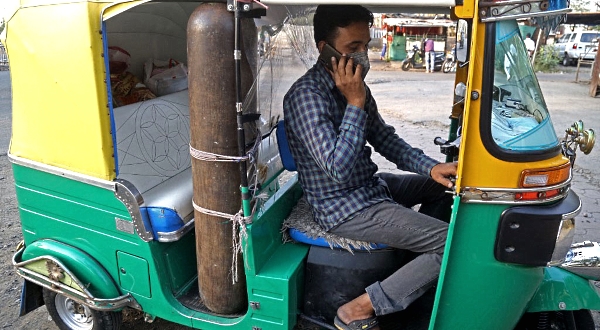 Mohammad Javed Khan speaks on his mobile phone inside his auto rickshaw converted into an ambulance with oxygen cylinder and accessories. AFP