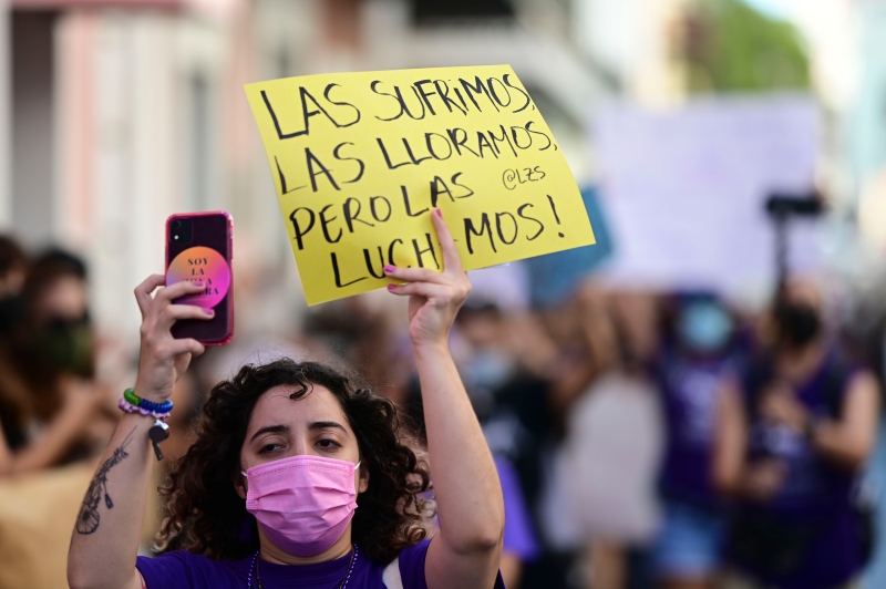 在反对维尔德霍暴力杀害凯希拉的示威活动中，一名女权主义团体的成员举着一个西班牙文纸牌，上边写道：“我们替她们难过，我们为她们哭泣，但我们为她们而战。”（美联社照片）