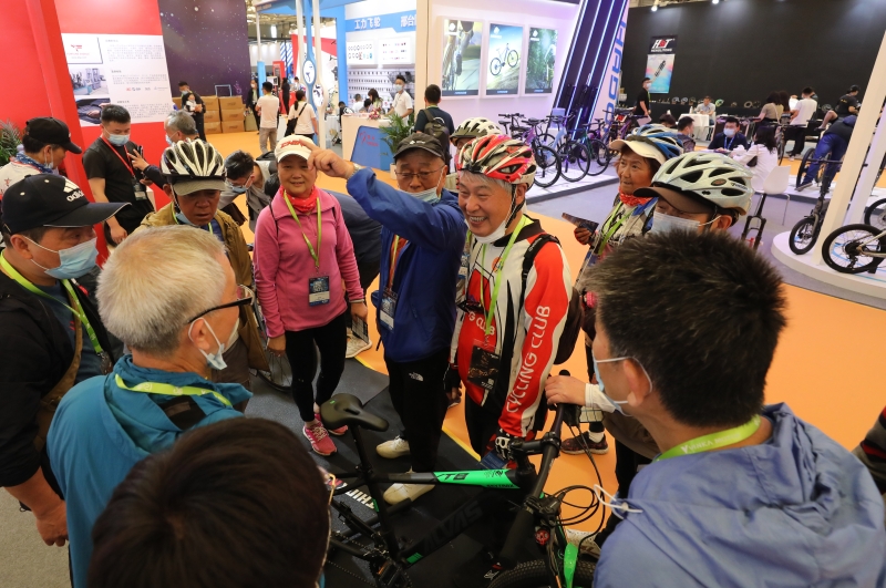 多名自行车爱好者身穿自行车武装在展会上与他人交流讨论。（图：新华社）