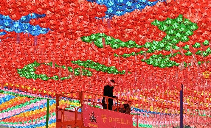 A worker attaches name cards with wishes of Buddhist followers to lotus lanterns at Jogye temple in Seoul ahead of celebrations marking Buddha's birthday. AFP