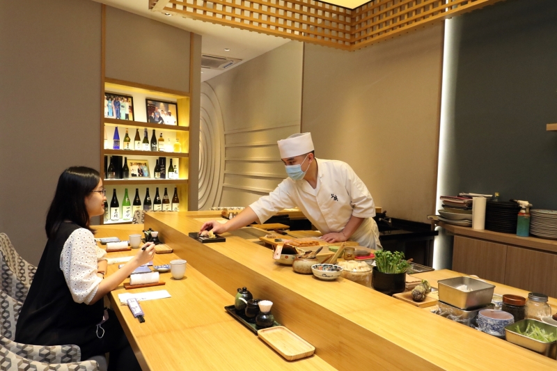 坐在吧台前品尝Omakase料理的食客，能够近距离欣赏师傅精湛的刀工，以及熟练的料理手艺。