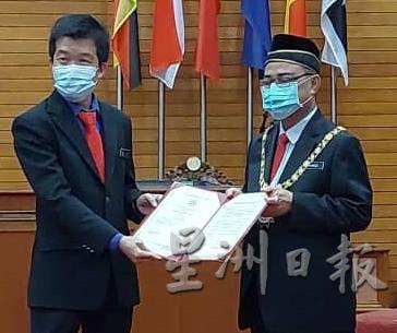 陈顺业（左）从市长手中接过新的委任状。

