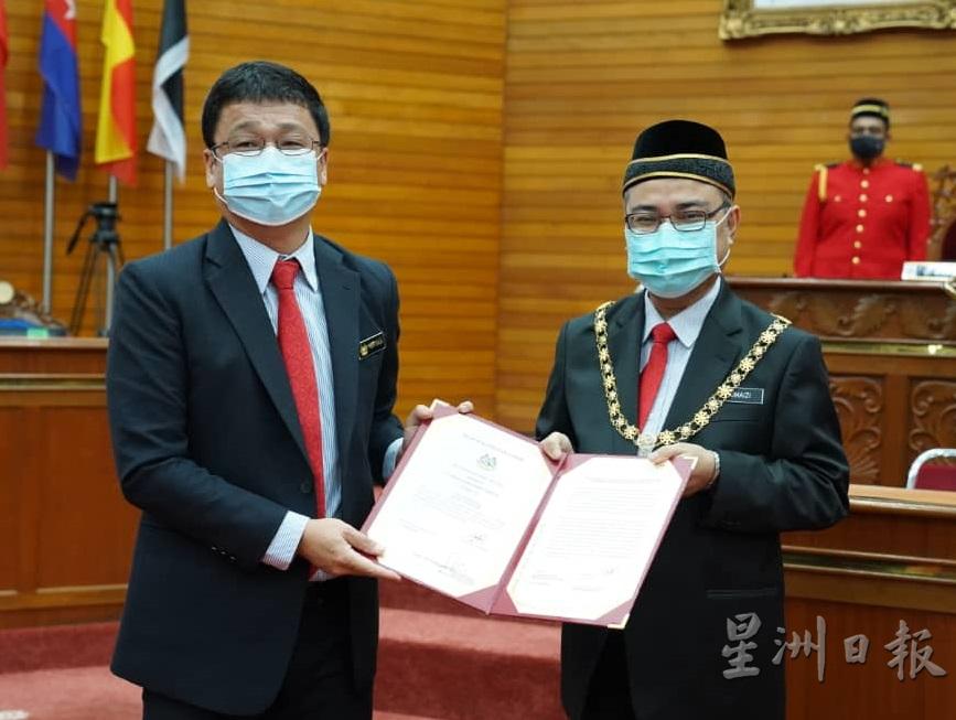 邱文传（左）从市长手中接领委任状，继续为民服务。