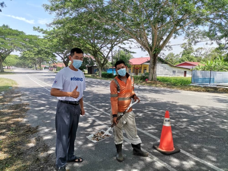 余德庆（左）感谢麻坡公共工程局迅速派员清理沙石，让民众安全使用公路。