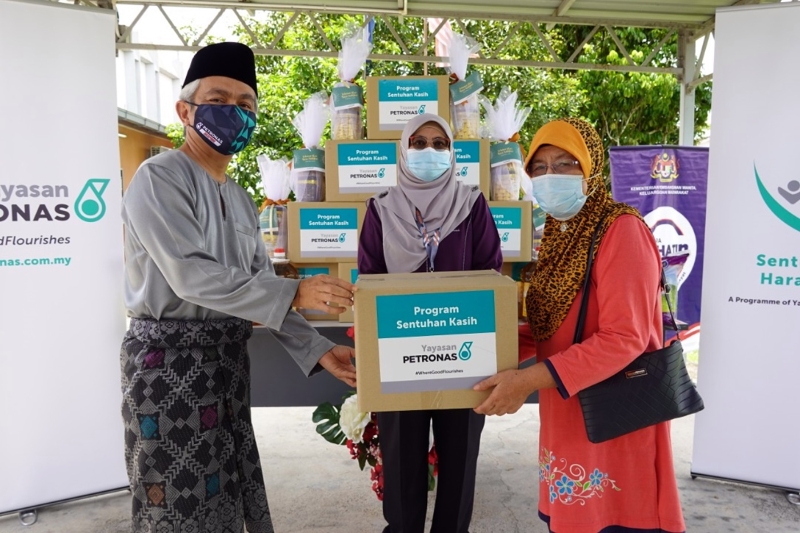 沙兹利（左）捐赠援助品予嘉米拉。中为峇株巴辖县福利局官员莎峇丽雅。