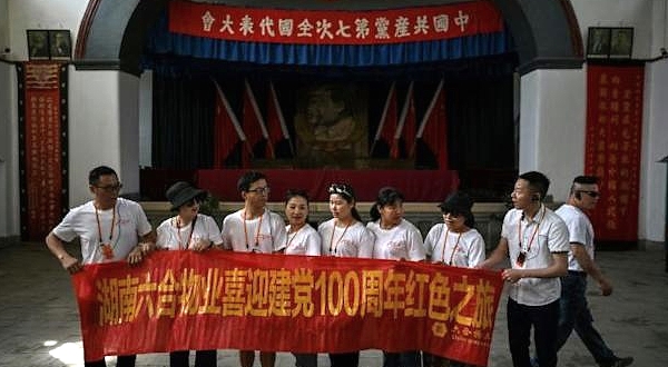 Tourists wearing commemorative T-shirts and unfurling a banner during a government-organized media tour in Yan'an. AFP