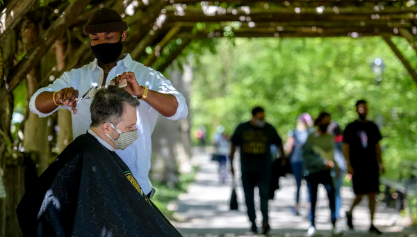 Barber Herman James cuts a client's hair under a pergola in Central Park. AFP