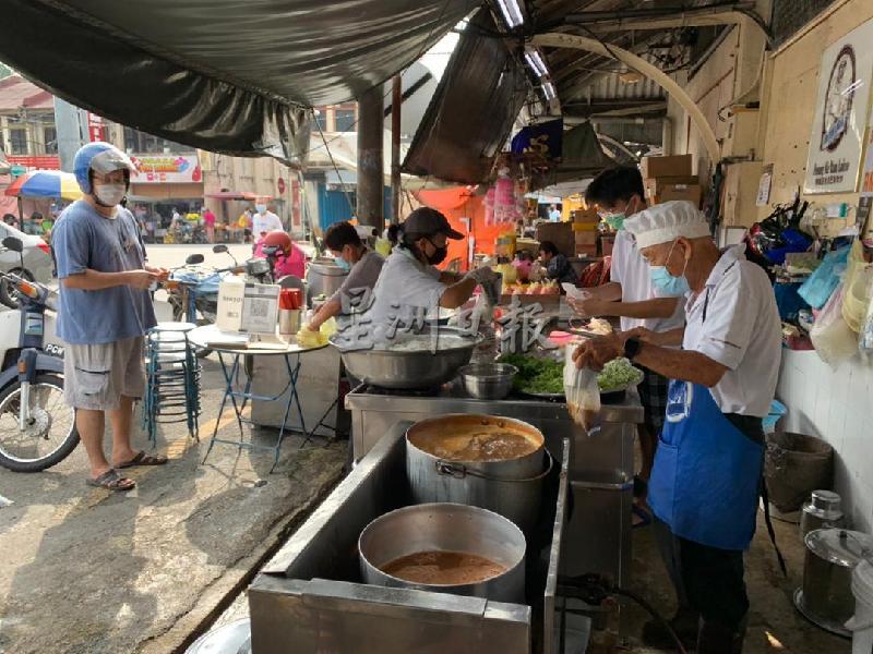 业者汪国祥（右）在暂停营业前亲力亲为顾客服务，献上美味的槟城叻沙。

