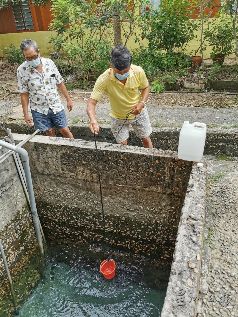 村民将绳索绑著的塑料桶放入井内取水。