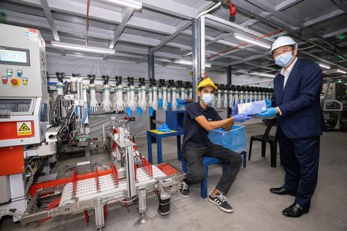 马星集团的手套已开始投产，集团董事经理丹斯里梁海金（右），从生产部负责人接过一盒MS手套。