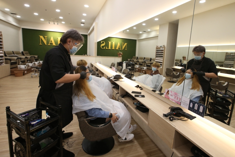 美发师“全幅武装”为顾客理发，做足防疫措施。