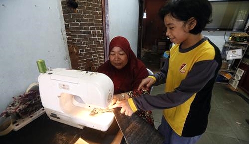 Lina at the sewing machine with her child. Lina at the sewing machine with her child.