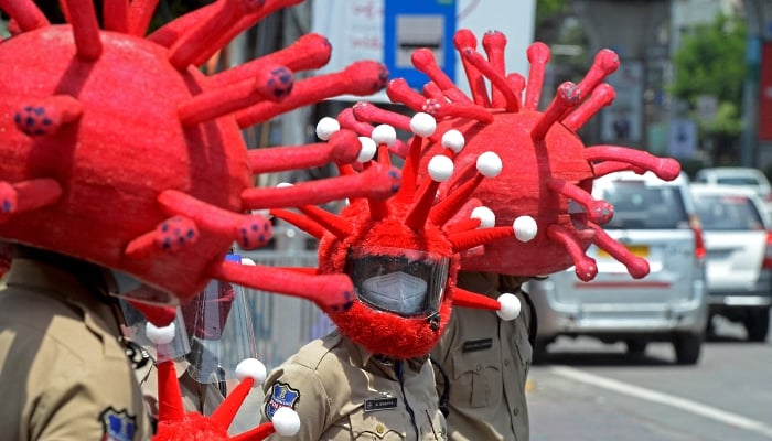 Police in COVID-19 headgear urge people to adopt safety protocols during an awareness campaign in Hyderabad, India. AFP