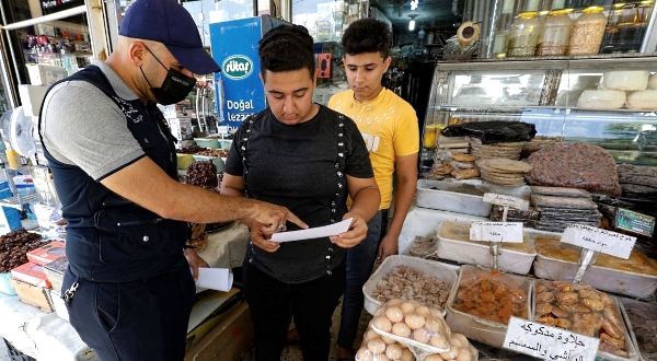 A member of Iraqi interior ministry's anti-fake news team speaks to a shopkeeper during an awareness campaign in Baghdad. AFP