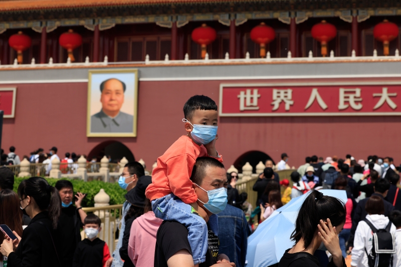 图为今年中国“五一”小长假期间北京天安门广场的旅游盛况。一名父亲背着小孩骑脖子排队等待入场。（美联社照片）