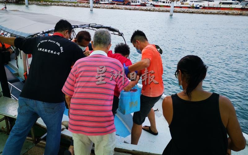岛民互相帮忙，扶著行动不便的年长者登上快艇。