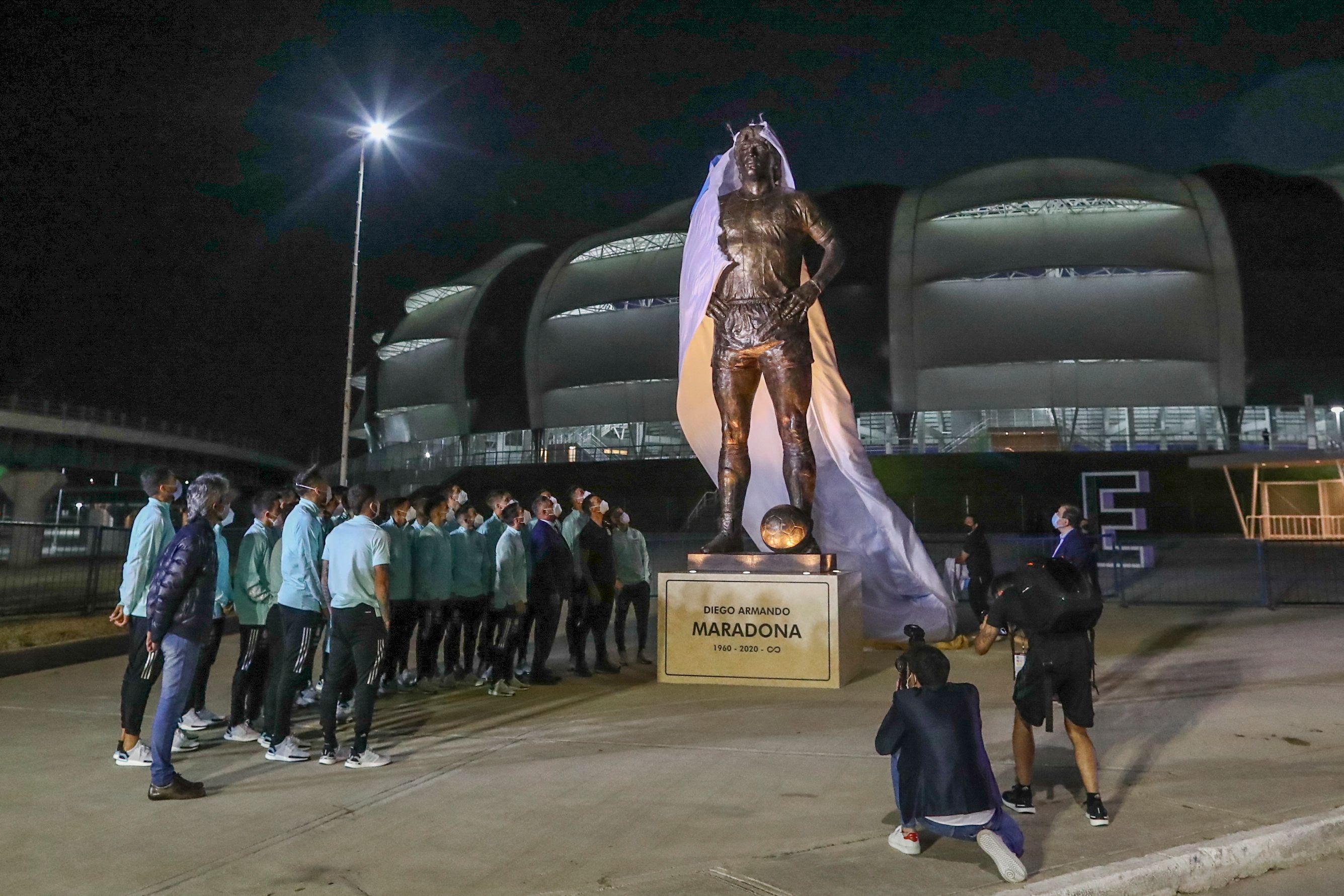 赛前，阿根廷队成员与阿足总成员，在体育场外揭开已故马拉多纳5米高的雕像。（法新社照片）

