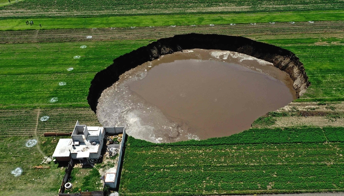 Aerial view of a sinkhole that was found by farmers in a field of crops in Santa Maria Zacatepec, Mexico on June 1, 2021. AFP