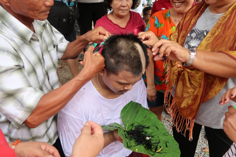 落发仪式首先由父母和亲属开始剃发，然后再由和尚师父或徒弟来做落发的动作。（莫咏焮摄）