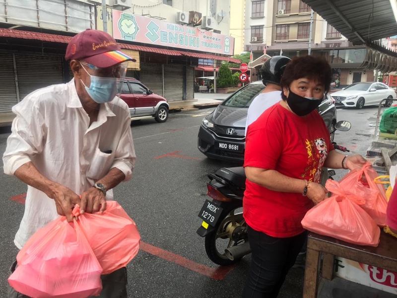 义工们把饭盒送至梁证法的报摊,在分发予有需要者。