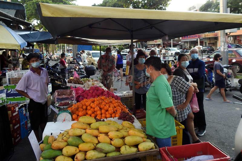公众在大路后巴刹附近排队买水果，时间是早上7时37分。