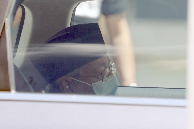 戴着口罩的马哈迪神情严肃，他在离开皇宫时，有向记者挥手打招呼。