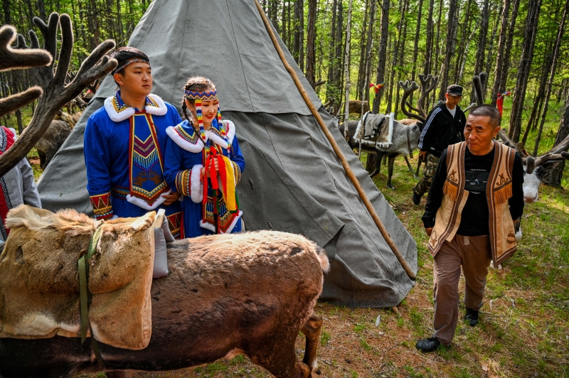 新郎侯磊和新娘何琦韩在鄂温克族传统的居所“撮罗子”前举行祝福仪式。（图：新华社）　