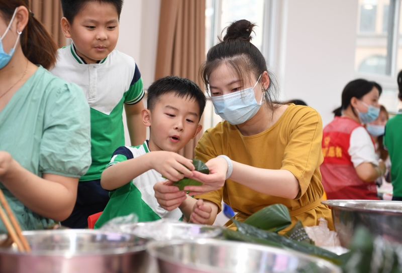 端午节临近，安徽省合肥市多家中小学、幼儿园举行丰富多彩的民俗文化活动，迎接传统佳节的到来。家长与孩子一起体验裹粽子的乐趣。