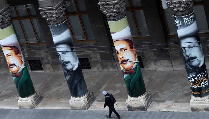A man walks past banners showing a portrait of Felix Salten on the columns of the Wien Museum in Vienna. AFP