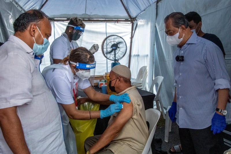 慕尤丁（右）前往敦拉萨镇视察当地的流动疫苗中心，以了解医疗人员为民众提供冠病疫苗接种的情况。