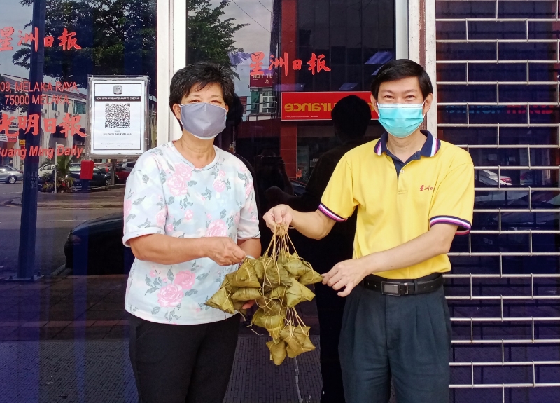 甲永春会馆妇女组署理主席林丽娟（左）移交50粒粽子给本报林安和。