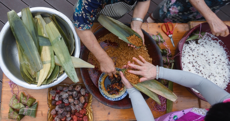 塘栖镇丁山河村的村民们在老字号老刀糕点铺的院子里包裹当地传统的「雌雄粽」。
