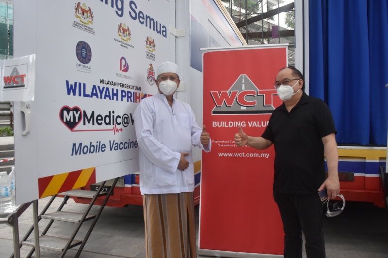 联邦直辖区部长丹斯里安努亚慕沙（左）也前来流动卡车接种疫苗计划现场巡视，右为WCT控股副董事经理曹英聪。