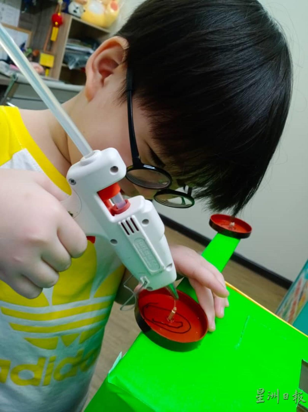 黄智轩全神贯注制作垃圾车。
黄智轩全神贯注制作垃圾车。