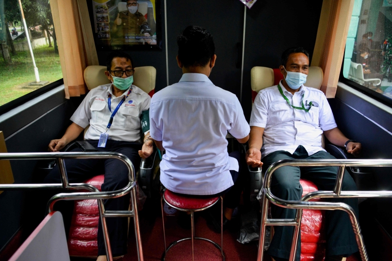在印尼，两名捐血者在流动巴士上捐上一份血。（图：法新社）