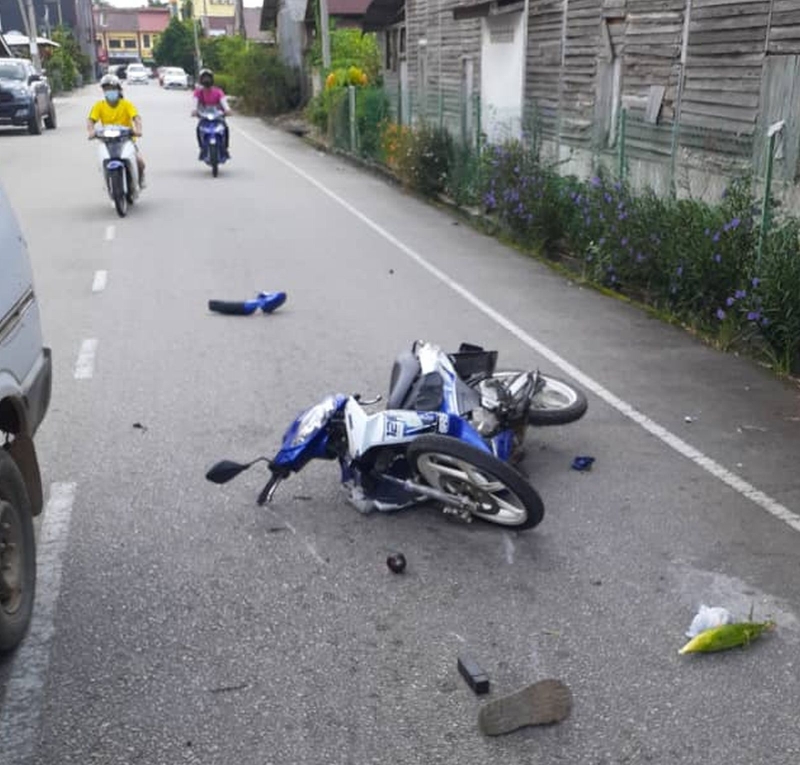 青年骑士的摩托车倒在路中，严重损坏。