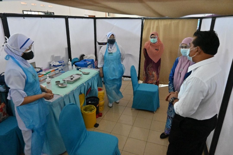 拉末（右一）向医护人员了解阿依摩力州选区中心疫苗接种的流程。