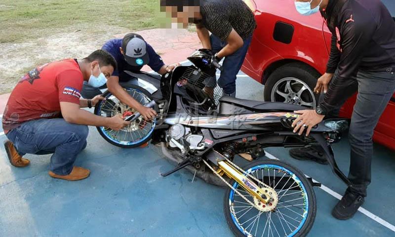 警员检查一辆摩托车的非法改装部件。
