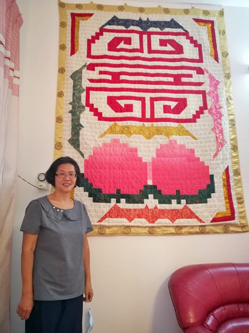张玉英旁边这幅作品，就是用了9个月时间缝制送给家婆的《五福捧桃》。