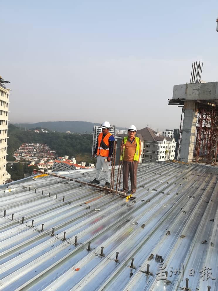 三年前尚未退休的郑冠英（右），在14层楼公寓的屋顶检视工程。