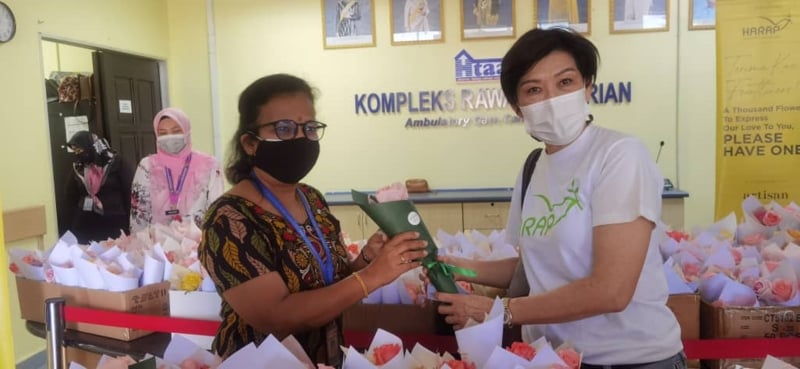 廖燕梅(右)赠送鲜花予拿汀歌丽医生，向全体前线医护人员表达谢意。
