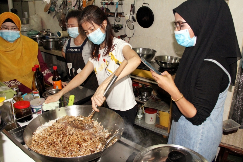 郭宝玉（右二）在峇株巴辖狮子会活动中，与友族同胞交流如何炒糯米及制作粽子。