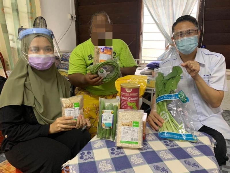 刘建利（右）及西蒂法蒂玛（左）赠送有机蔬菜及食品给乳癌患者嘉岚妮（中）。