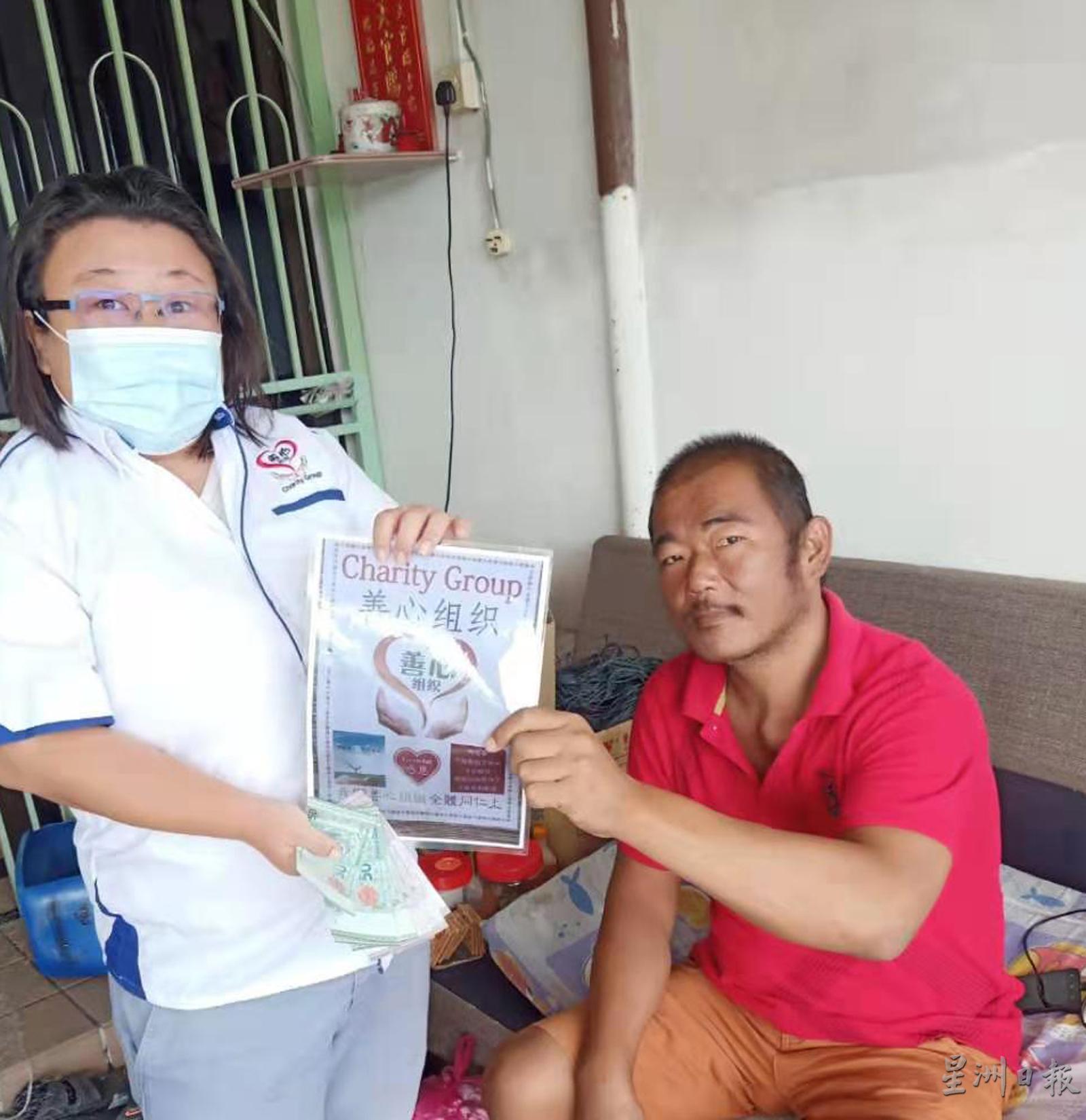 庄清锫（左）代表善心组织移交第一个月的500令吉援助金给陈泰昌（右）。