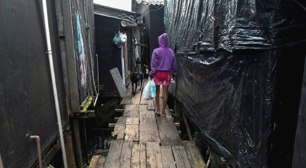 A resident walks along a platform on stilts at the Dique da Vila Gilda favela in Santos. AFP