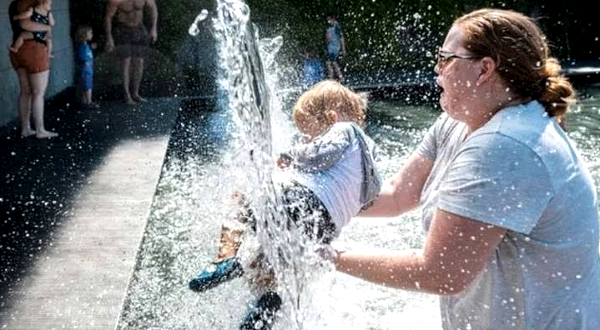 A woman holds a young child under a waterfall at a park in Washington, DC as a heatwave moves over much of the US. AFP A woman holds a young child under a waterfall at a park in Washington, DC as a heatwave moves over much of the US. AFP