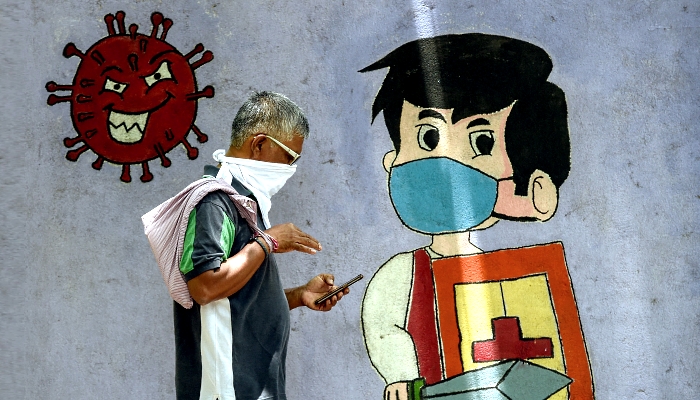 A man walks past a wall mural depicting a boy wearing a face mask while holding a sword and a shield to spread awareness about the coronavirus in Mumbai, India. AFP