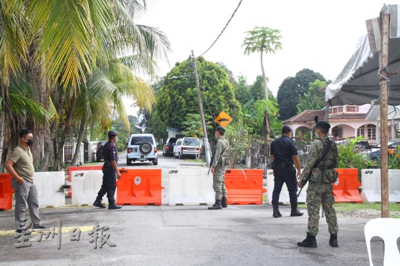 数名军警人员驻守在文良港甘榜布亚的主要出入口，并用路障围起出入口。 （本报摄影：黄玲玲））